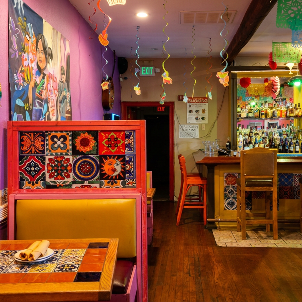 Vibrant Mexican restaurant interior with purple walls, colorful decor, booths, and a fully stocked bar.
